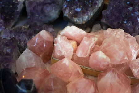 Close-up of natural rose quartz surrounded by purple minerals. Concept of natural stone texture and...