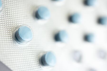 Macro little blue pill in foil blister. Close-up medicine tablets with selective focus