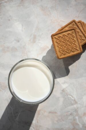 Glass of milk and butter cookies on the kitchen table in a bright daylight. Top view, fast lunchの写真素材