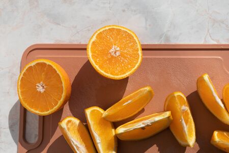 Top view of fresh cut oranges on brown cutting board. Many slices, natural light. Natural beverages.