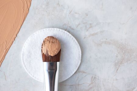Make up brush with BB cream, CC cream or foundation on white cotton round and luxury marble background, top view. Daily makeupの写真素材