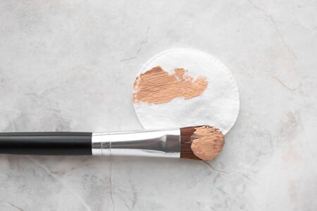 Make up brush and cotton round with BB cream or foundation on luxury marble background, top view. Daily makeupの写真素材