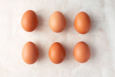 Brown organic eggs on marble background, top view. Easter minimalism concept の写真素材