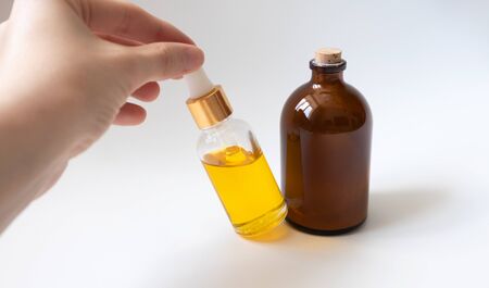 Woman hand take glass bottle with oil serum on white background. Skincare cosmetic productsの写真素材