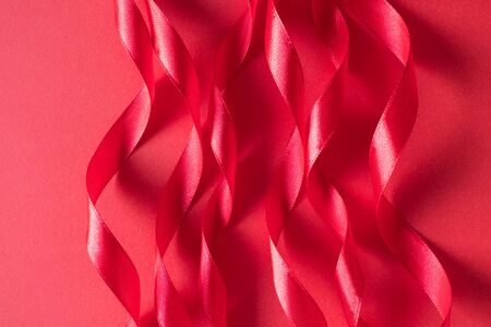 Bright pink color curl satin ribbon on paper background. Minimal beautiful flat lay backdrop for Valentine's day cardの写真素材
