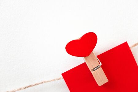 Close-up red heart wooden clothespin on rope twine on white wall, horizontal. Detail of garland for Valentine's day decoration with copy space. Concept loveの写真素材