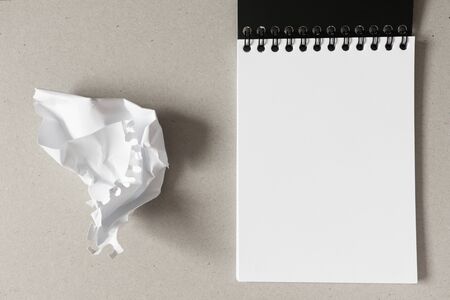 Open notebook with blank white paper sheet and crumpled paper ball on gray background. Horizontal, above. Concept stress, mistakesの写真素材