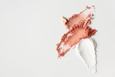 Blusher, eyeshadow and transparent face powder smudges on white background with copy space, close-up. Nude tone textured powder mineral cosmetic product for natural daily makeupの写真素材