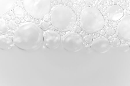 Border from foam bubbles from soap, shampoo or cleanser on white background with selective focus and copy space. Macroの写真素材