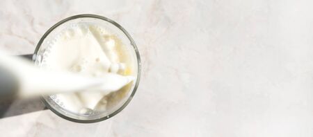 Freshness milk filling glass on marble table background with copy space, above. Drink splash, close-up. Dairy product banner formatの写真素材