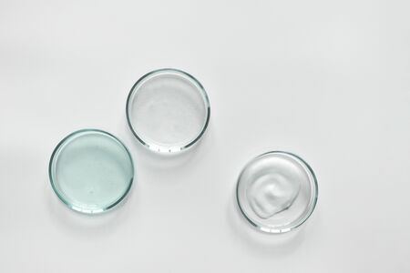 Glass petri dish with different cosmetic products on white background. Shampoo, hair conditioner or...