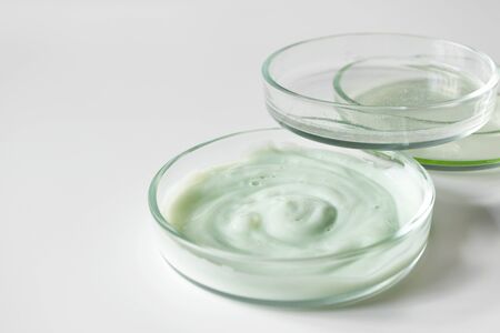 Variety cosmetic products in petri glass dishes on white background with selective focus. Body care and hygieneの写真素材