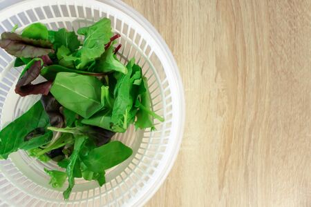 Salad and spinach leaves on wooden kitchen table with copy space, top view. Cooking dinner, lifestyle. Fresh healthy eating and vitamin foodの写真素材