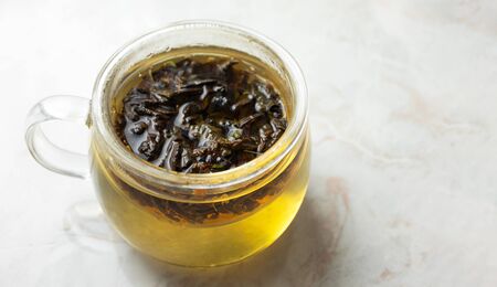 Infusing herbal tea in glass mug on marble table, close-up
