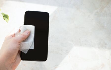 Clean and disinfect with antiseptic wipes for mobile phone. Hand holding smartphone