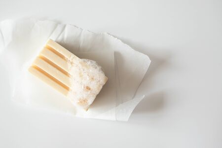 Soap bar with foam bubbles on paper on white background, top view. Health care, body care and...