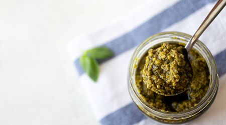 Tasty pesto sauce in spoon with copy space, above. Italian basil sauce banner horizontal formatの写真素材