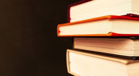 Stack of books with selective focus on black background with copy space in vintage style. Banner...