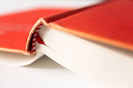 Close-up open book in red cover with selective focus on white background. Concept education,...