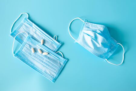 New and used protective face masks, pills and copy space on blue background. COVID epidemic. Flu and...