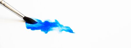 Blue watercolor stain texture and paintbrush on white paper with selective focus and copy space. Hobby and art horizontal banner formatの写真素材