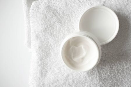 Open moisturizer cream or body lotion on white bathroom towel background and copy space. Beauty treatment skin care product, aboveの写真素材