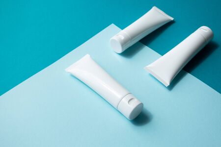 Moisturizer hand cream white plastic tubes mockup on blue trendy paper background, isometric. Blank...