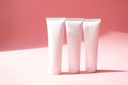 Three moisturizer creams containers on cute pink background. Beauty product mockup with trendy shadow. Concept delicate, lightness and pure skincareの写真素材