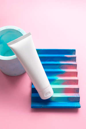 White moisturizer cream tube on abstract concrete decor on cute pink background and copy space for...