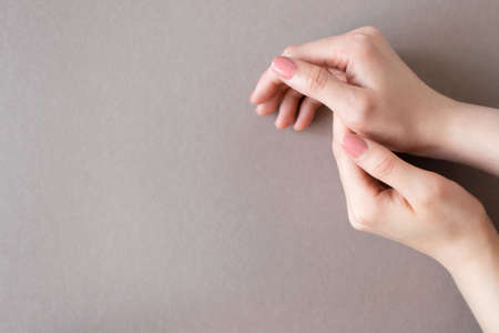 Tender female hands on brown background with nude pink manicure on nails and copy space. Beauty...