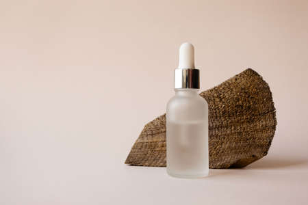 Facial hyaluronic moisturizer transparent serum fluid in bottle with pipette and textured defocused wooden tree cut surface on beige background. Eco organic natural beauty skincare mockup productの写真素材