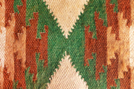 Knitted ethnic ornament pattern. Abstract craft woven textile rug interior details. Close-up texture carpetの写真素材