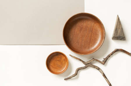 Empty wooden plates and tree branches on two neutral beige colors paper backgrounds, top view....