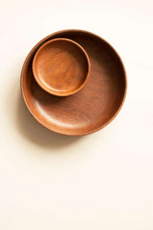 Empty two wooden plates, above. Round dishes on light beige background with copy space. Mockup for...