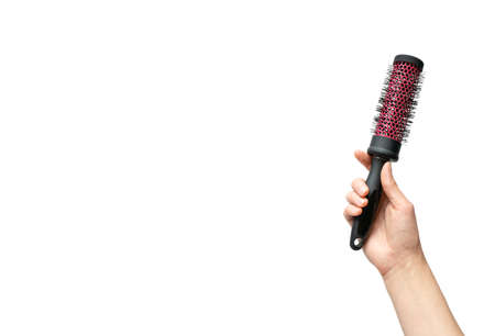 Woman hand holding round hairbrush isolated on white background with copy space, horizontal. Haircare conceptの写真素材