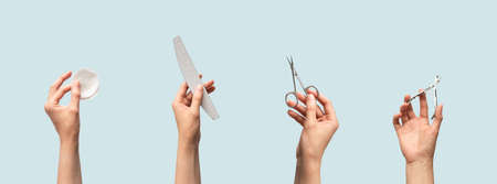 Female hands holding manicure and pedicure tools isolated on blue background with copy space, horizontal banner format. Cotton pads, nail file, scissors and cuticle nippers in human handの写真素材
