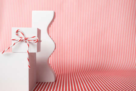 White gift box with red white striped twine cotton string rope and abstract geometric shape objects...