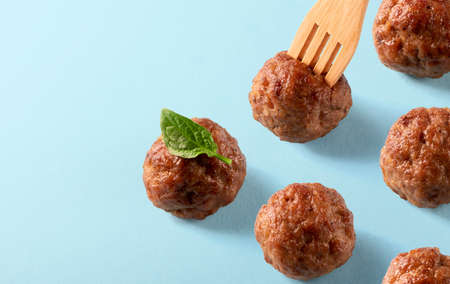 Italian cuisine beef meatballs with basil leaf and wooden fork on blue background. Template for menu, recipe or packing. Delicious food, isometricの写真素材