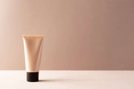 Tube tonal foundation makeup mockup on beige background with copy space. BB or CC cream container...