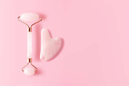 Quartz facial massager and gua sha on pink background with copy space banner format, top view. Trendy skincare facial massager tools 3d vector realistic illustrationのイラスト素材