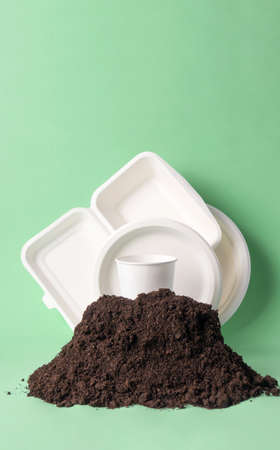 Set single-use tableware popular non-plastic alternatives in ground heap, vertical. Compostable or biodegradable dinnerware conceptの写真素材