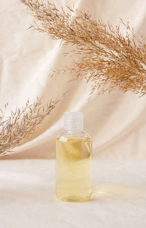 Hydrophilic cleanser oil on linen drapery and dry plant. Makeup remover cosmetic beauty skincare product mockup. Concept eco organic cosmetic with natural extractの写真素材