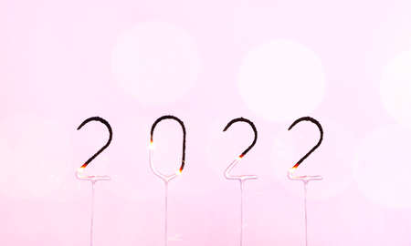 2022 burning sparklers number on pink background with blurred bokeh light. Happy New Year and Merry Christmas banner with copy spaceの写真素材