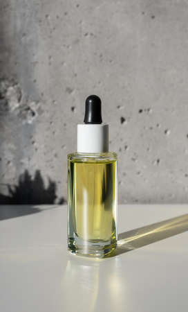 Facial yellow oil serum glass bottle with pipette mockup and shadow succulent shape, still lifeの写真素材