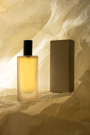 Perfume bottle and wrapping box on crumbled paper beige backgroundの写真素材