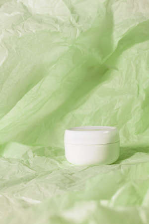 Cream bottle skin care beauty cosmetic product on green crumbled paperの写真素材