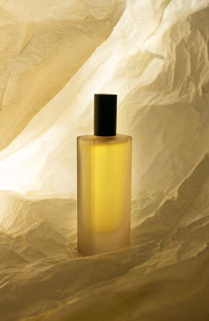 Perfume bottle on crumbled paper beige backgroundの写真素材