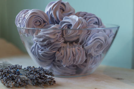 Violet marshmallow in form of rose in a large glass bowl with lavender flowers in frontの写真素材
