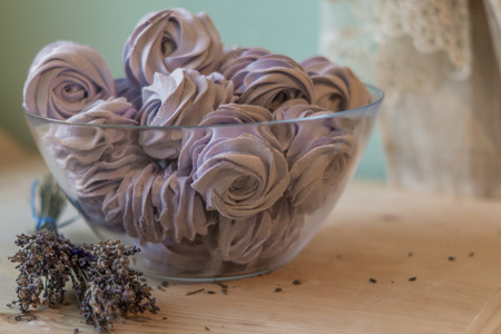 Violet marshmallow in a large glass bowl with lavender flowers in front,   stays on a wooden table and turquoise background.の写真素材