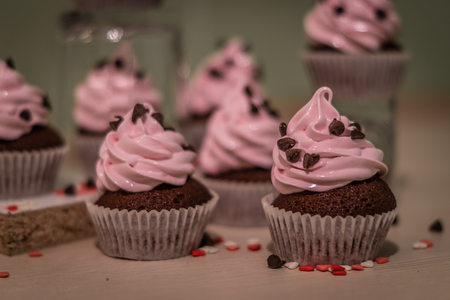 Chocolate muffins with pink whipped cream and cocoa nibsの写真素材
